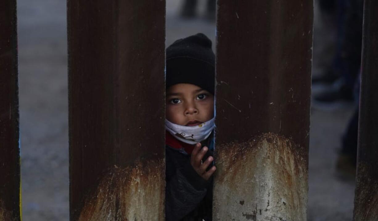 A young boy, part of several asylum seeking families participating in a Las Posadas event at the U.S.-Mexico border wall, peers into the U.S. from Agua Prieta, Mexico Tuesday, Dec. 15, 2020, seen from Douglas, Ariz. People on each side of the border celebrate Las Posadas as they have done for decades, a centuries-old tradition practiced in Mexico re-enacts Mary and Joseph&#039;s search for refuge in Bethlehem through songs, with several of the families attending stuck south of the border, their lives in limbo with U.S. proceedings suspended amid the COVID-19 pandemic. (AP Photo/Ross D.