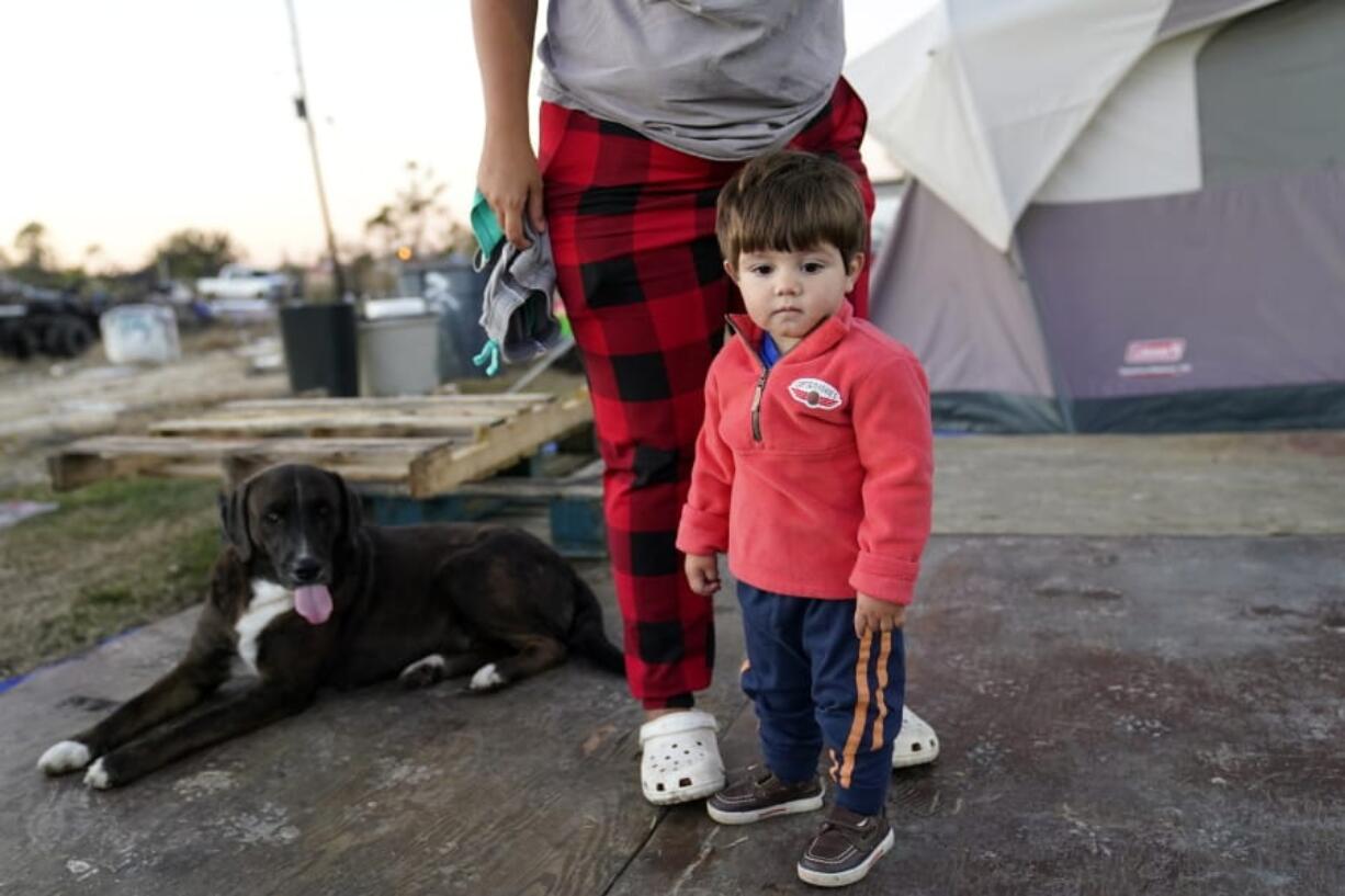 Katelyn Smith stands with her one year old son Ricky Trahan, III, as she prepares to change his clothes, as their family lives in a camper and tents where their home was destroyed, in the aftermath of Hurricane Laura and Hurricane Delta, in Lake Charles, La., Friday, Dec. 4, 2020.