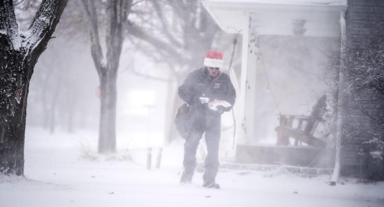 Mail carrier Dennis Niles braves the blowing snow as blizzard like conditions hit Osseo and the Twins Cites on Wednesday, Dec. 23, 2020 in Osseo, Minn.