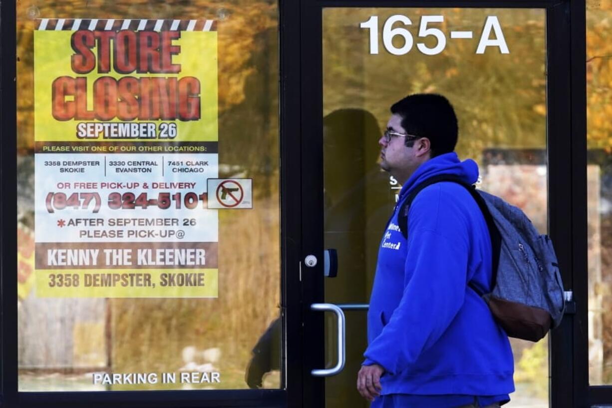 FILE - In this Friday, Nov. 6, 2020, file photo, a man walks past a closed store in Wilmette, Ill., amid the coronavirus pandemic. Responses to the coronavirus pandemic and police brutality dominated legislative sessions in 2020 and led to many new laws that will take effect in the new year. (AP Photo/Nam Y.