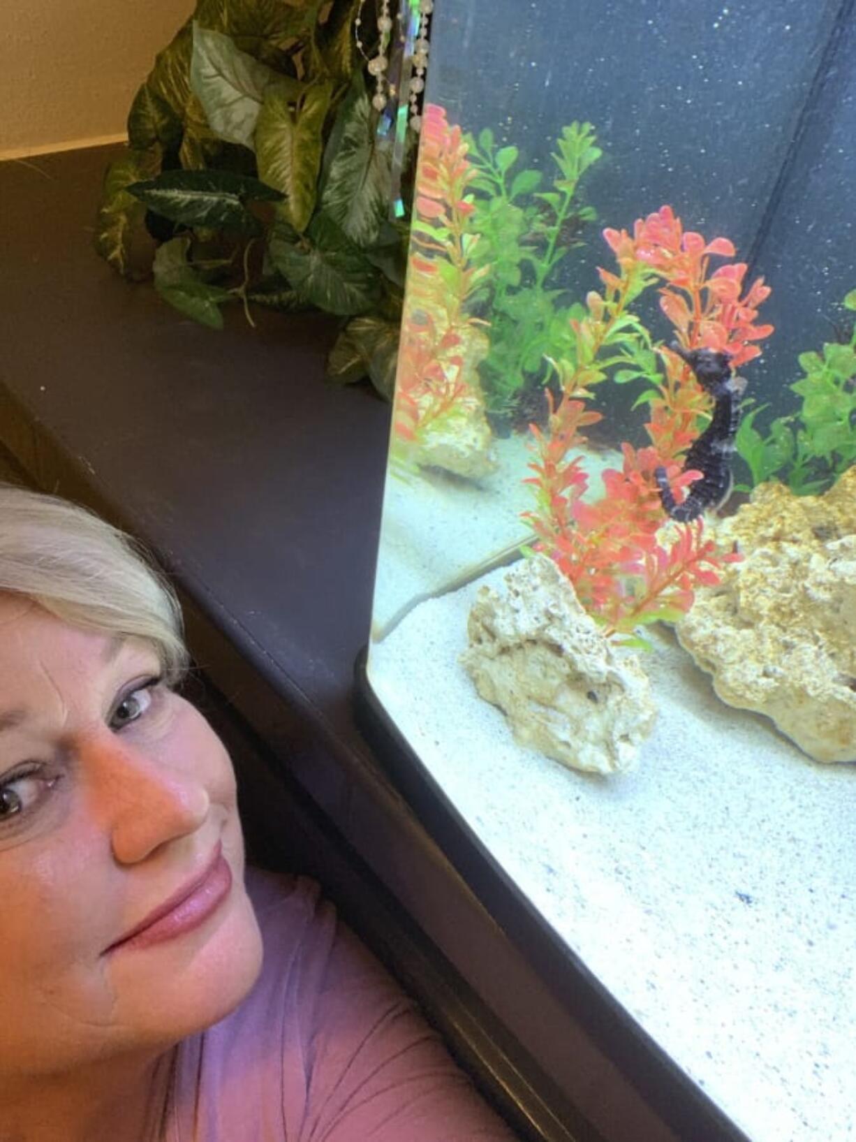 Carol Benge poses next to her home aquarium with her seahorse Louie, Tuesday, Nov. 24, 2020 in Chiefland, Fla. In September, Benge noticed that the seahorse was having trouble swimming. She took him to the University of Florida veterinary school where they diagnosed the problem. He was put in a hyperbaric chamber, and with one treatment, Louie was cured.