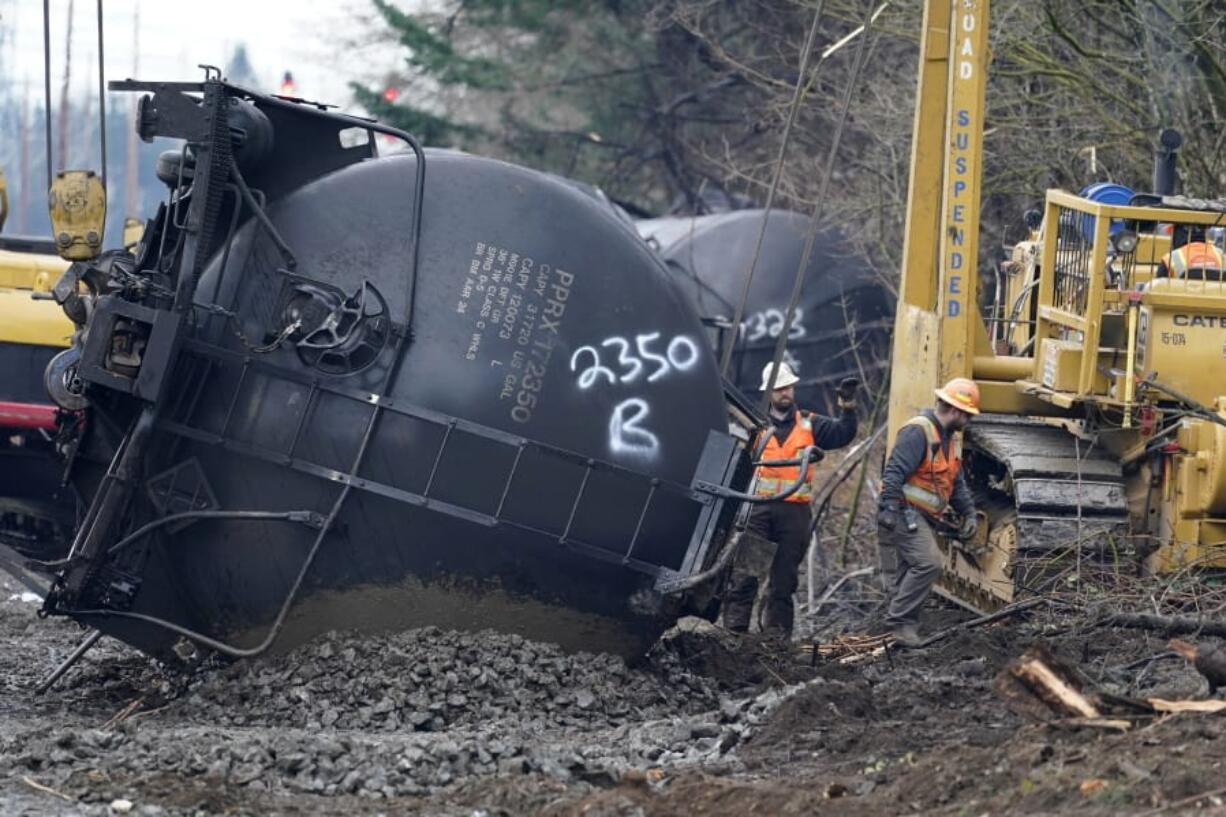 Workers use heavy equipment to begin to move one of several train cars which had been hauling crude oil and derailed a week earlier, Tuesday, Dec. 29, 2020, in Custer, Wash. The cause of the derailment of the oil cars Dec. 22 in Whatcom County is still unknown. A spokesperson for BNSF Railways said three cars ruptured, spilling an unknown amount of crude oil onto the ground.