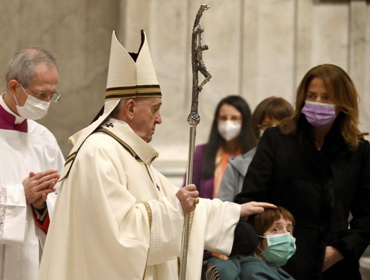 Pope Francis caresses a boy as he arrives to celebrate Mass on Christmas eve, at St. Peter&#039;s basilica at the Vatican, Thursday, Dec. 24, 2020.