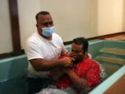 Pastor Luke Jesse of the First Marshallese Throne in Jouj church wears a mask as he baptizes Danny Baro on Sunday, Nov. 22, 2020, in Noel, Mo. After the coronavirus swept through the town of about 1,800 people, the First Marshallese Throne in Jouj and four other churches that worship at the building of the Community Baptist Church experienced a faith revival with an estimated 50 baptisms in three months.