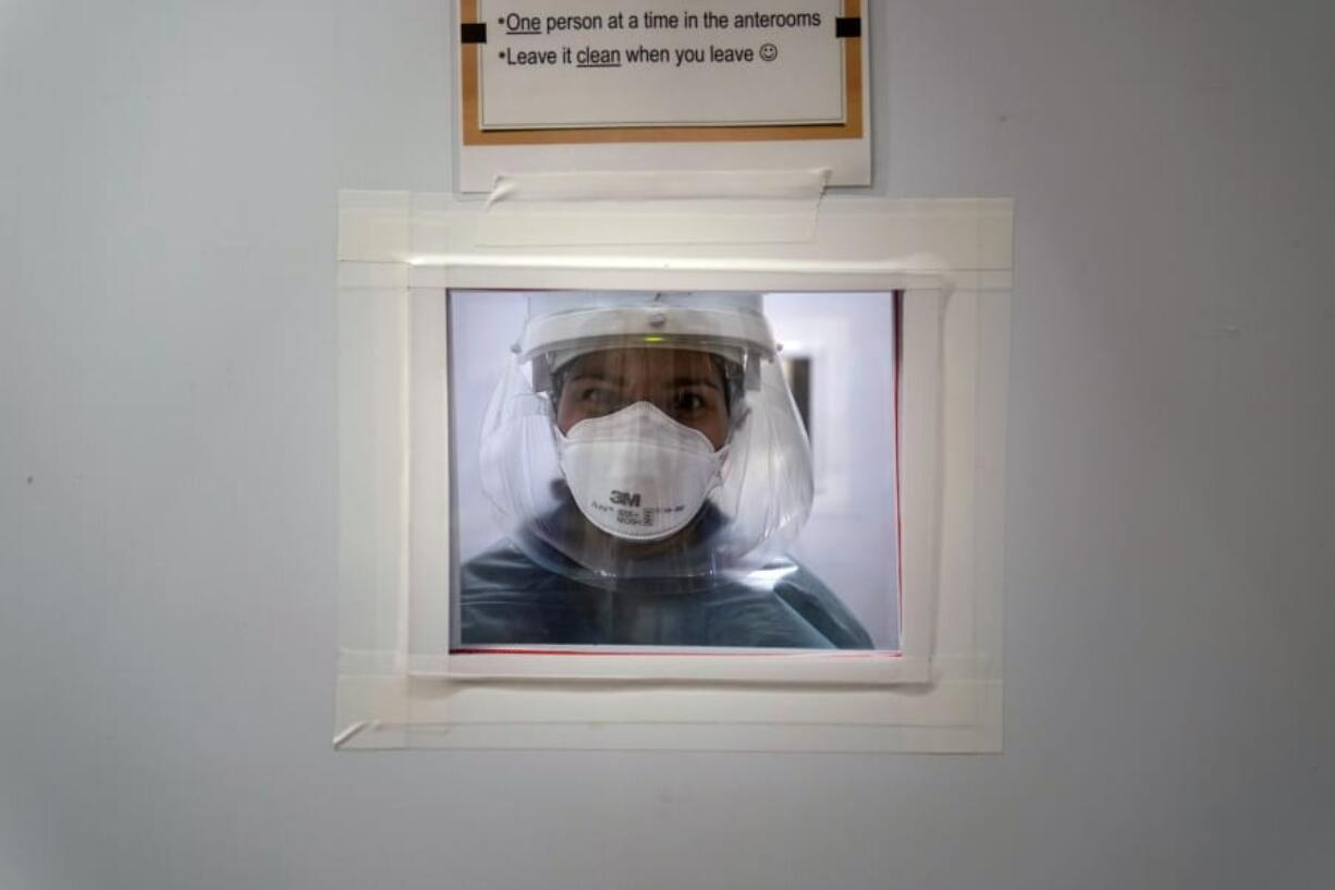 Registered nurse Nicole Grecco looks through a small window while working in a COVID-19 unit at Mission Hospital in Mission Viejo, Calif., Monday, Dec. 21, 2020. (AP Photo/Jae C.