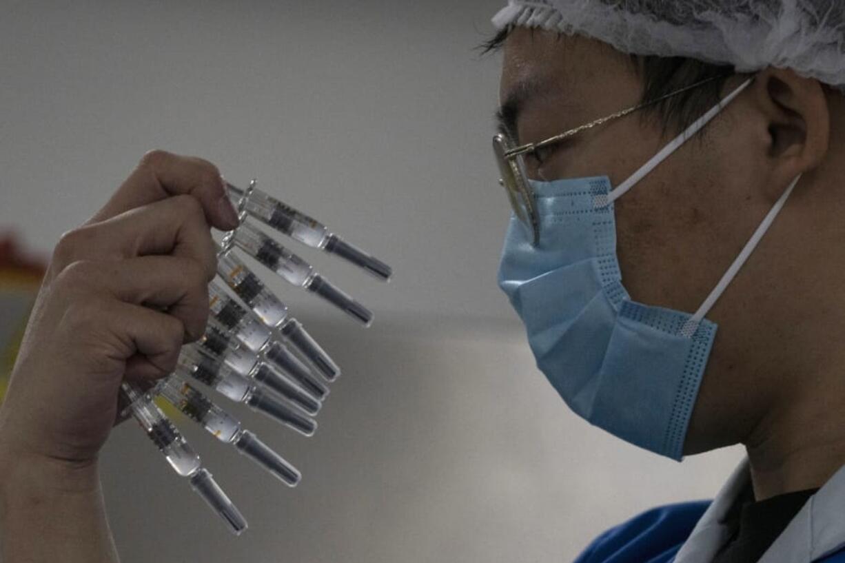 A worker inspects syringes of a vaccine for COVID-19 produced by Sinovac at its factory in Beijing on Thursday, Sept. 24, 2020. With rich countries snapping up supplies of COVID-19 vaccines, some parts of the world may have to rely on Chinese-developed shots to conquer the outbreak. The question: Will they work?