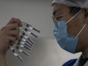 A worker inspects syringes of a vaccine for COVID-19 produced by Sinovac at its factory in Beijing on Thursday, Sept. 24, 2020. With rich countries snapping up supplies of COVID-19 vaccines, some parts of the world may have to rely on Chinese-developed shots to conquer the outbreak. The question: Will they work?