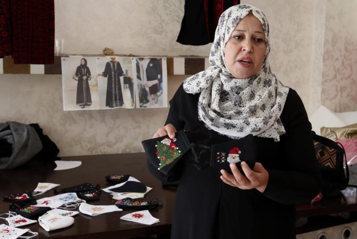 Suhad Saidam, shows stitched images of Santa Claus and Christmas on face masks at her sewing workshop in Gaza City, Monday, Dec. 14, 2020. In the blockaded Gaza Strip, the Christmas season is giving a boost to Saidam&#039;s business that produces pandemic face masks decorated with holiday symbols. They also have provided a small boost several dozen families in a Palestinian enclave run by the Islamic militant Hamas group.