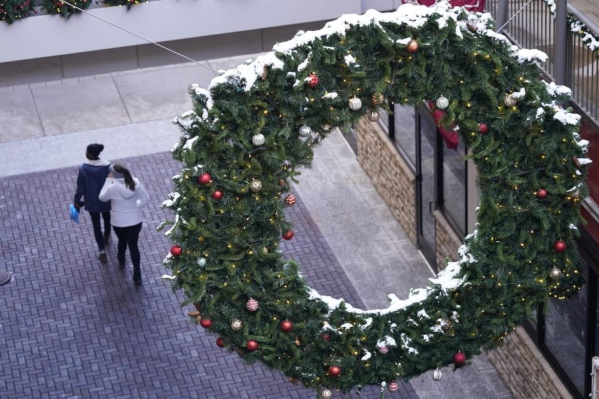 Shoppers wear face masks while in search of after-Christmas bargains in shops in the Denver Pavilions Tuesday, Dec. 29, 2020, in downtown Denver.