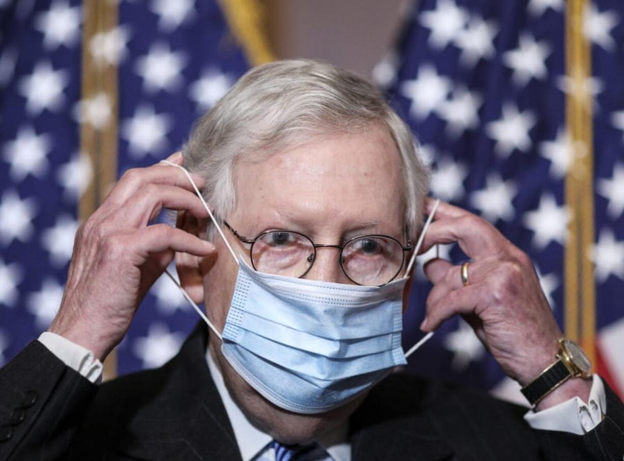 Senate Majority Leader Mitch McConnell of Ky., removes his face mask as he arrives for a news conference with other Senate Republicans on Capitol Hill in Washington, Tuesday, Dec. 15, 2020.