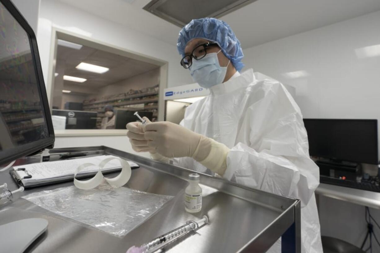 A pharmacist labels syringes in a clean room where doses of COVID-19 vaccines will be handled, Wednesday, Dec. 9, 2020, at Mount Sinai Queens hospital in New York. The hospital expects to receive doses once a vaccine gets the emergency green light by U.S. regulators.