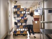 FILE - In this April 4, 2020, file photo, Bethany White, Providence Sacred Heart Medical Center supply chain manager, helps stabilize a shifting pallet of protective gowns as the third of five shipments of PPEs arrived at Sacred Heart from the state in Spokane.