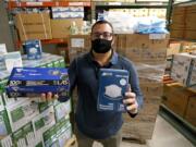 Ray Bellia holds up personal protective masks and gloves, used by medical and law enforcement professionals, in the warehouse of his Body Armor Outlet store, Wednesday, Dec. 9, 2020, in Salem, N.H. Bellia&#039;s store rapidly evolved into one of the nation&#039;s 20 largest suppliers of personal protective equipment to states this past spring, according to a nationwide analysis of state purchasing data by The Associated Press.