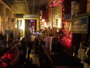 Bartender Alex Wright takes a phone order for liquor on his cell phone while tending the bar behind a protective plastic barrier separating him from patrons at Barbes, a popular music venue and bar converted to a bottle shop and mostly-outdoor service bar, Tuesday, Dec. 1, 2020, in New York.