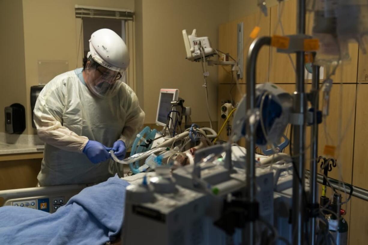 FILE - In this Nov. 19, 2020, file photo, respiratory care practitioner Scott Hoagland checks on a COVID-19 patient at Providence Holy Cross Medical Center in the Mission Hills section of Los Angeles. California&#039;s hospitals are being overwhelmed by a surge of coronavirus patients and some say the worst is yet to come. (AP Photo/Jae C.