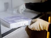 University of Washington Medical Center Pharmacy Manager Christine Meyer puts a tray of doses of the Pfizer-BioNTech COVID-19 vaccine into the deep freeze after the vaccine arrived Monday at the University of Washington Medical Center&#039;s Montlake campus in Seattle.