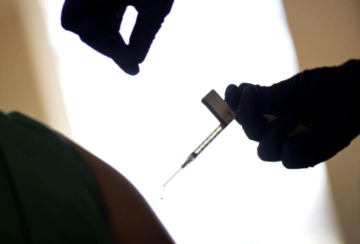 FILE - In this Tuesday, Dec. 15, 2020, file photo, a droplet falls from a syringe after a health care worker was injected with the Pfizer-BioNTech COVID-19 vaccine at a hospital in Providence, R.I. The U.S. COVID-19 vaccination campaign has begun, and the few available doses are mostly going into the arms of health care workers and nursing home residents. But what about in January, February and March, when more shots are expected to become available? Who should get those doses?