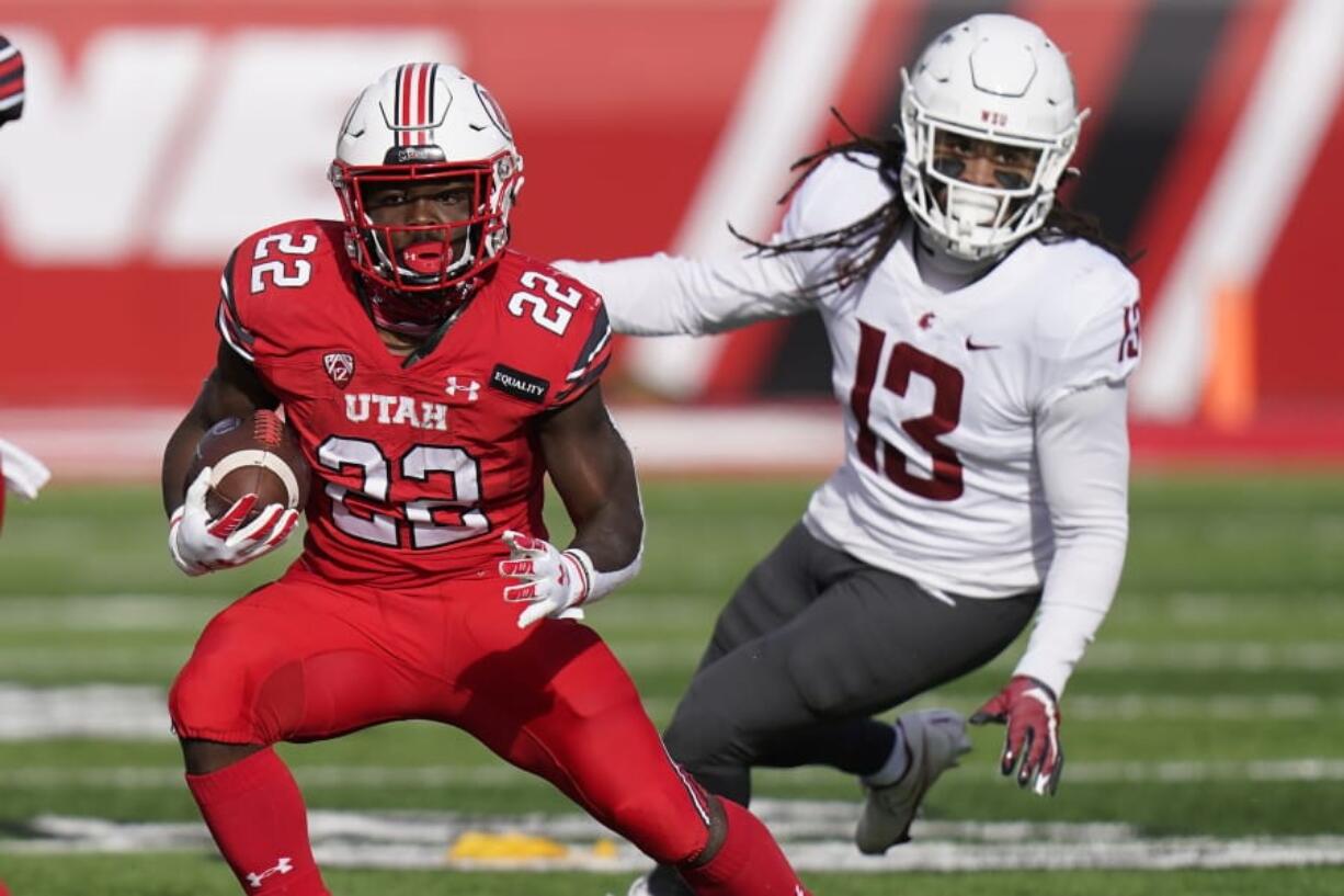 Utah running back Ty Jordan (22) runs from Washington State linebacker Jahad Woods (13) during the first half of an NCAA college football game Saturday, Dec. 19, 2020, in Salt Lake City.