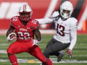 Utah running back Ty Jordan (22) runs from Washington State linebacker Jahad Woods (13) during the first half of an NCAA college football game Saturday, Dec. 19, 2020, in Salt Lake City.