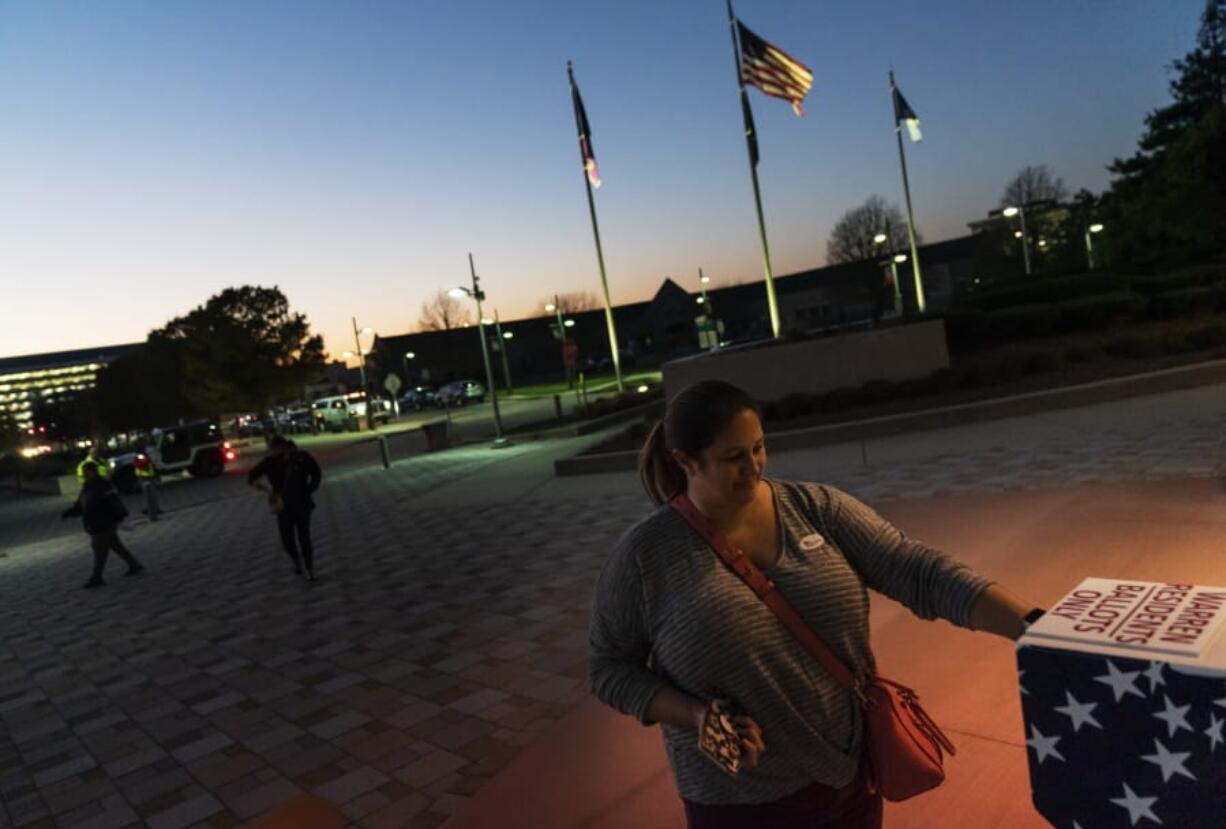 FILE - In this Tuesday, Nov. 3, 2020 file photo, Wendy Gill inserts her absentee ballot at a drop-off box as the sun sets on Election Day outside City Hall in Warren, Mich. The pandemic triggered wholesale changes to the way Americans voted in 2020, but that&#039;s no guarantee measures making it easier to cast ballots will stick around for future elections.