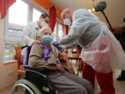 Doctor Bernhard Ellendt, right, injects the COVID-19 vaccine to nursing home resident Edith Kwoizalla, 101 years old, in Halberstadt, Germany, Saturday, Dec. 26, 2020. The first shipments of coronavirus vaccines have arrived across the European Union as authorities prepared to begin administering the first shots to the most vulnerable people in a coordinated effort on Sunday. The vaccines developed by BioNTech and Pfizer arrived by truck in warehouses across the continent on Friday and early Saturday after being sent from a manufacturing center in Belgium before Christmas.