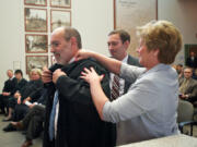 Judge Rich Melnick gets help with his robe from his wife, Lori Melnick, and son Ben Melnick, after he was sworn in as a judge of the Washington State Court of Appeals, Division II at the Clark County Public Service Center on March 26, 2014. Melnick recently retired and was replaced by Judge Bernard Veljacic.