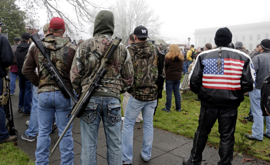 Demonstrators with rifles slung across their backs attend a rally by gun-rights advocates to protest a new expanded gun background check law in Washington state Saturday, Dec. 13, 2014, in Olympia, Wash. Saturday&#039;s protest was called the &quot;I Will Not Comply&quot; rally, and those attending said they will openly exchange firearms in opposition to the state&#039;s new voter-approved universal background check law, Initiative 594. The law, which took effect on Dec. 4, requires background checks on all sales and transfers, including private transactions and many loans and gifts.
