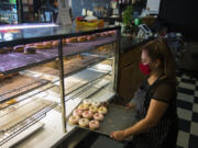 Jessica Sanchez, co-owner of Tonallis Doughnuts &amp; Cream, looks over a selection of fresh doughnuts. Business has been slow for Tonallis during the pandemic, but Sanchez said she has faith that it will pick up.