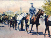 A Vancouver Barracks mule train returns from the Lacamas Creek artillery range (renamed Camp Bonneville in 1909) along the city streets around 1908. The convoy heads down 10th Street (now Evergreen Boulevard) toward the barracks packing ammunition. The troopers belong to the U.S. Army Mountain Gun Battery, 2nd Field Artillery Regiment stationed here between 1904 and 1913. The steeple of the First Presbyterian Church and the minister&#039;s home rise in the background.