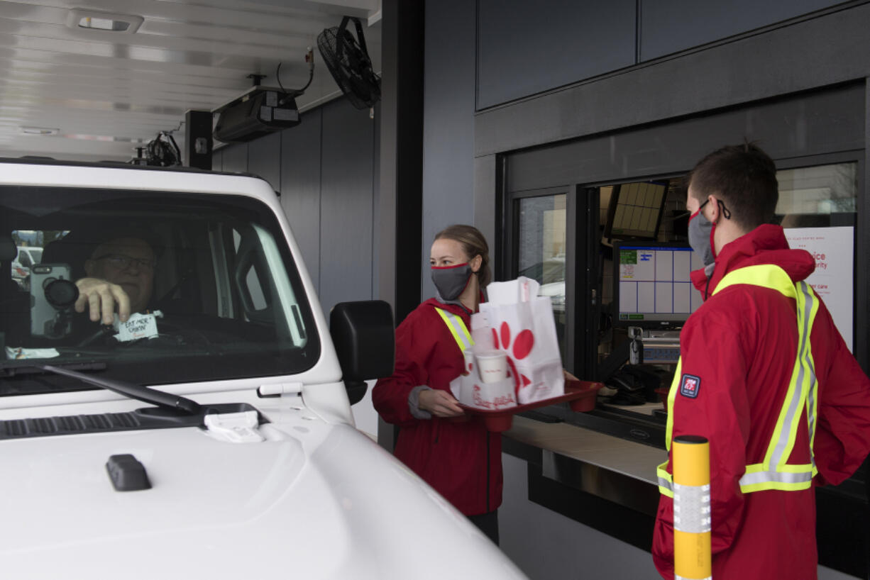 Keith Hallett of Vancouver, from left, who was one the first customers through the drive thru at the new Chick-fil-A restaurant, picks up his order from Tanya Bogdanov as Sawyer McIntosh lends a hand at Vancouver Mall on Thursday morning, January 7, 2021.