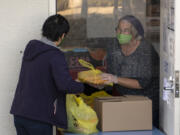 Volunteer Libby Bryant helps a food recipient at FISH Westside Food Pantry of Vancouver. The pantry serves about 1,200 families, or 3,500 people every month, Executive Director James Fitzgerald said.