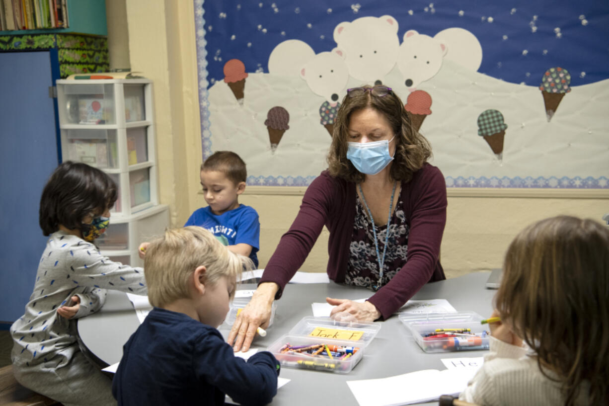 Teacher Elaine Walker works with 4-year-old students, from left to right, Tristan Stevenson, Paxton Seto, Jack Forslund and Lucy Snowden on Tuesday at the Camas-Washougal Parent Co-Op Preschool. Walker has taught at the preschool for 20 years and has faced many challenges this year amid the pandemic, namely teaching kids words with a mask on. &quot;Sometimes I step back away from the table to be able to show them the way my mouth is shaped when saying a word,&quot; she said.