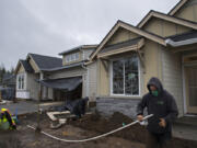 Marco Perez of Tapias Landscaping, right, works in the front yard of a home under construction in the Parker&#039;s Abby development in Vancouver on Tuesday. New home construction is booming in Vancouver, but the region still faces a housing supply crunch. Below, signs mark two homesites that have been sold at the Stonehaven development in Vancouver.