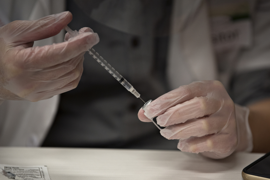 Jordan Tran of CVS Pharmacy prepares a COVID-19 vaccine for staff at Touchmark at Fairway Village in Vancouver.