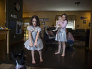 Andrea Heldt of Vancouver looks on while her daughter, Nora, 7, bonds with puppy Thea as her other daughter, Kylee, 9, plays the piano Wednesday afternoon. The girls used to be enthusiastic about school, but they have been less engaged as remote learning drags on. The Heldt family tries to have fun together to keep things positive during the pandemic.