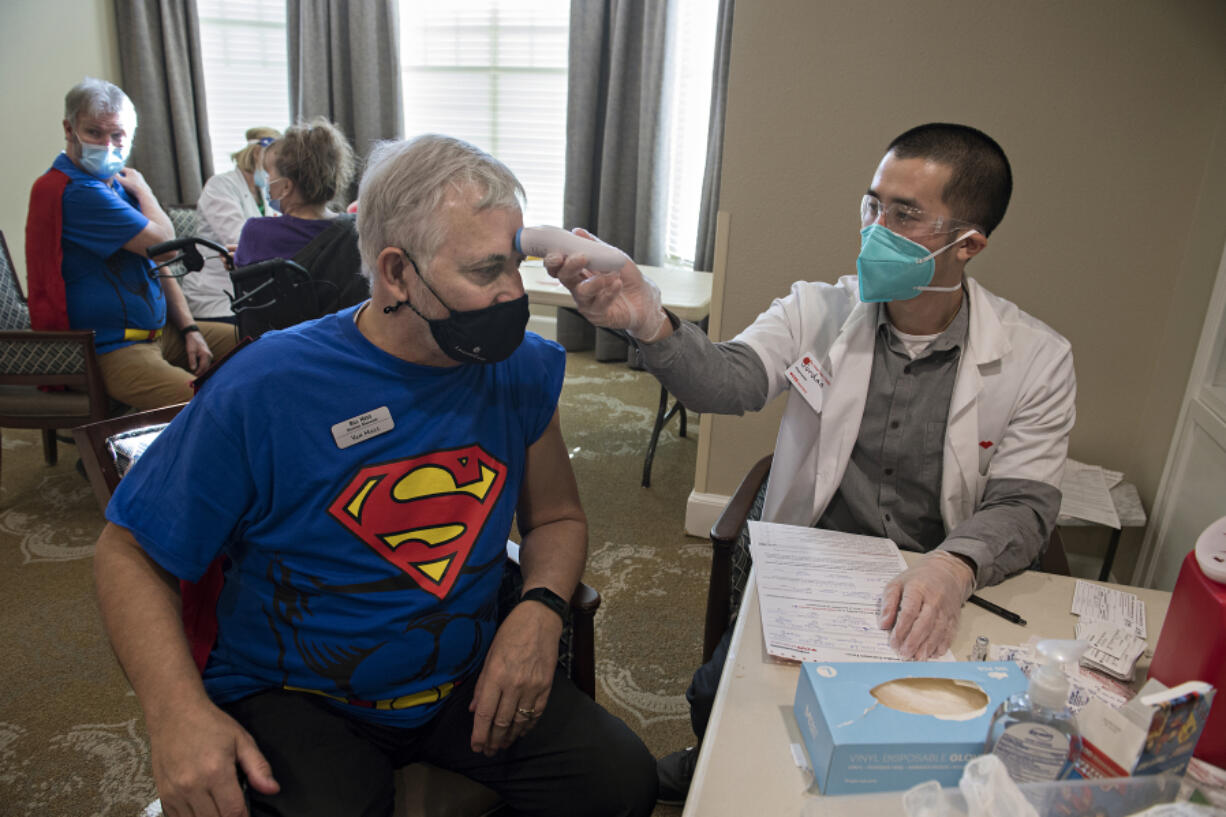 Van Mall Retirement General Manager Bill Hess, left, harnesses his superpowers while getting his COVID-19 vaccination from Jordan Tran of CVS Pharmacy on Friday at Van Mall Retirement. Hess was among the 205 staff and residents that were vaccinated last week. Van Mall had a superhero theme to celebrate staff and residents.