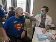 Van Mall Retirement General Manager Bill Hess, left, harnesses his superpowers while getting his COVID-19 vaccination from Jordan Tran of CVS Pharmacy on Friday at Van Mall Retirement. Hess was among the 205 staff and residents that were vaccinated last week. Van Mall had a superhero theme to celebrate staff and residents.