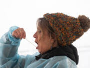 Staffer Kelly Lund swabs her mouth while demonstrating the process to conduct a self-administered oral COVID-19 test at the new Tower Mall rapid testing site in Vancouver. The site offers free COVID-19 tests in a socially distant drive-thru or walk-up configuration.