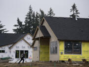 A worker lends a hand at a house under construction in the Felida Overlook neighborhood Wednesday morning. A set of energy code updates is set to take effect Feb. 1, and builders have expressed concern that the new rules could drive up construction costs at a time when the COVID-19 pandemic has already pushed up home prices.