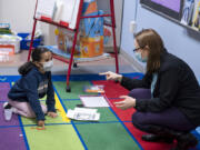 Kindergartner Camila Huesos-Delgado works on a math assignment while teacher Jessica Roth helps at Captain Strong Primary School in Battle Ground.