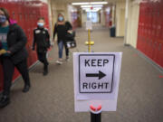 Eighth grader Brooke Pisors, 13, from left, leads sixth grader Tucker Troffer, 11, and his mom, Megan, on a school tour as signs in the hallway at Liberty Middle School in Camas help keep students socially distanced on Wednesday afternoon. Schools have designed personalized COVID-19 mitigation plans to keep students and staff safe.