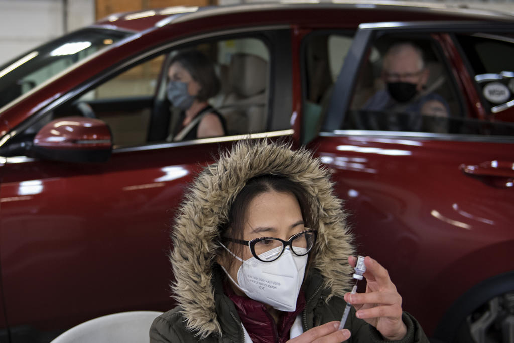 Tram Nguyen, an intern with Safeway, foreground, prepares doses of COVID-19 vaccine for visitors in line such as Peggy and Bob Swenson of Camas, background, at the Clark County Event Center at the Fairgrounds on Tuesday morning, January 26, 2021.