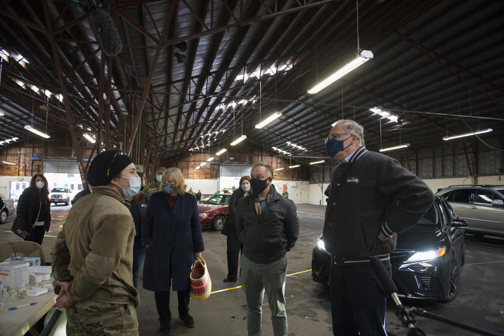 Pvt. Brei Plumb, who is a medic in the Washington National Guard, left, talks with Washington Secretary of Health Dr. Umair Shah, second from right, and Gov. Jay Inslee, right, as they tour the mass vaccination site at the Clark County Fairgrounds on Thursday morning, January 28, 2021.