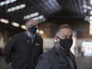 Gov. Jay Inslee, background left, listens as Washington Secretary of Health Dr. Umair Shah speaks to the media during a tour the COVID-19 mass vaccination site at the Clark County Fairgrounds on Thursday morning, January 28, 2021.