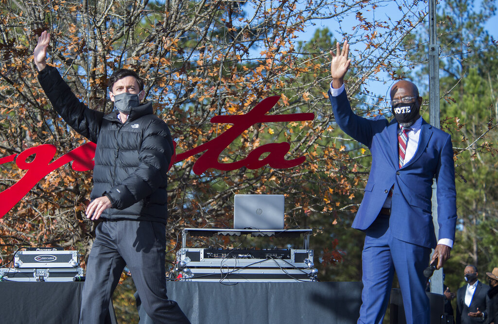 Jon Ossoff, left, and Raphael Warnock wave to the crowd during a campaign rally in Augusta, Ga., Monday, Jan. 4, 2021. Democrats Ossoff and Warnock are challenging incumbent Republican Senators David Perdue and Kelly Loeffler in a runoff election on Jan. 5.