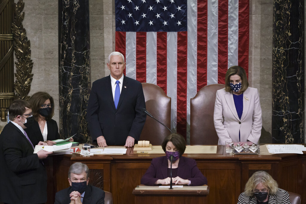 Vice President Mike Pence and Speaker of the House Nancy Pelosi, D-Calif., read the final certification of Electoral College votes cast in November's presidential election during a joint session of Congress after working through the night, at the Capitol in Washington, Thursday, Jan. 7, 2021. Violent protesters loyal to President Donald Trump stormed the Capitol Wednesday, disrupting the process. (AP Photo/J.