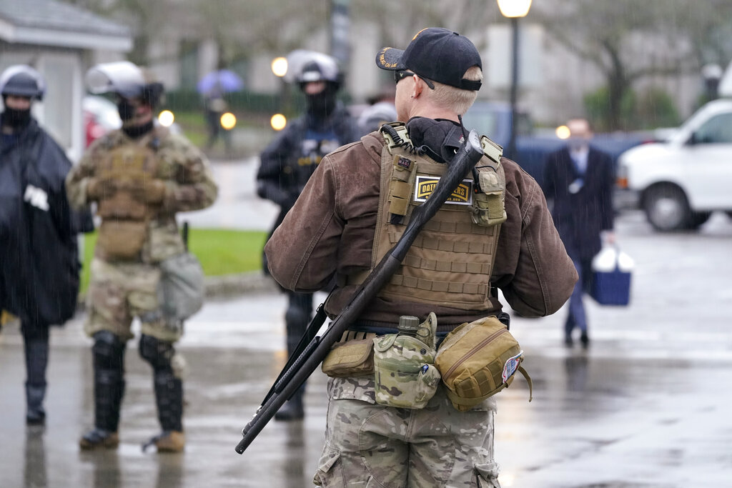 An armed protester stands outside the Capitol Monday, Jan. 11, 2021, in Olympia, Wash. According to organizers, some protesters are unhappy the Legislature will meeting virtually and in sessions not open to the public, due to the COVID-19 pandemic, during the 2021 session which opens Monday. Washington Gov. Jay Inslee activated members of the National Guard this week to work with the Washington State Patrol to protect the Capitol campus. (AP Photo/Ted S.