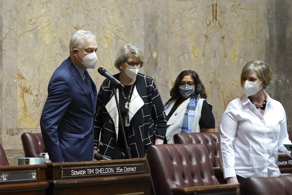 State Sen. Reuven Carlyle, left, D-Seattle, votes in favor of adopting new Senate rules as other senators, who had to come to the floor from the gallery and nearby offices, wait near him to cast their own votes, Monday, Jan. 11, 2021, at the Capitol in Olympia. At right is Sen. Annette Cleveland, D-Vancouver. (AP Photo/Ted S.