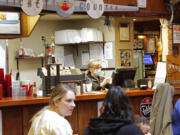 Restaurant co-owner Liz Mitchell works behind the bar at the Carver Hangar in Boring, Ore., on Jan. 6, 2021. As coronavirus deaths soar, a growing number of restaurants like Carver Hangar in states across the country are reopening in defiance of strict COVID-19 rules that have shut them down for indoor dining for weeks, or even months.