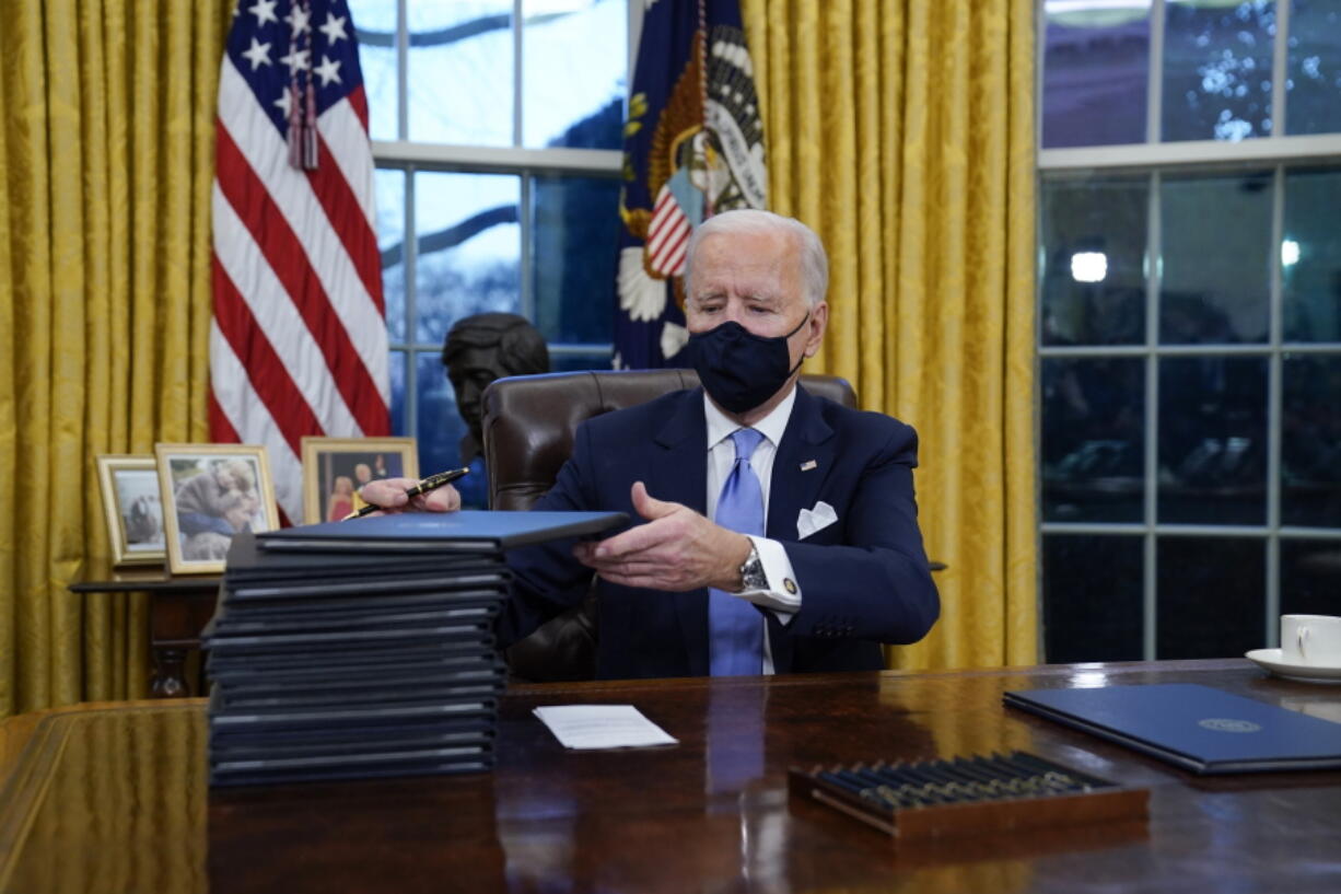 President Joe Biden signs his first executive orders in the Oval Office of the White House on Wednesday, Jan. 20, 2021, in Washington.